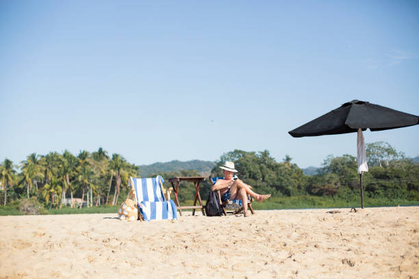 istock Mature man reading on the beach 1383977711