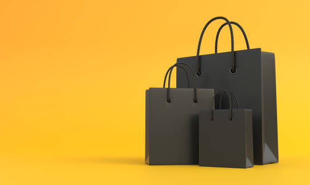 istock Black shopping bags on a yellow background with copy space 1383982131