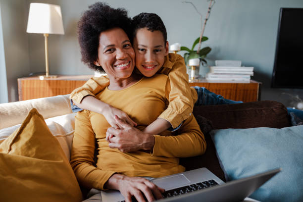 istock Modern mother trying to work on laptop at home while her son is hugging her 1383985706
