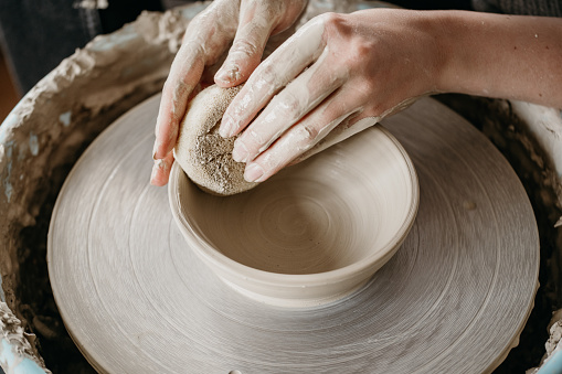 woman hand shaping ceramic bowl with sponge on throwing wheel