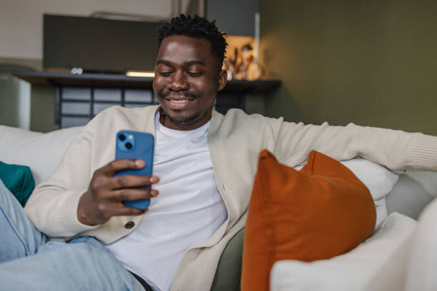 istock Young African-American man using mobile phone at home 1383987280