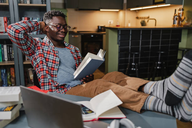 istock African-American man reading a book at home 1383989000