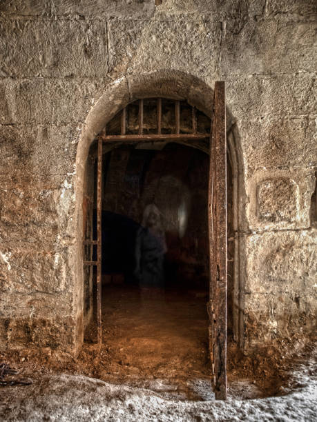 An Eerie Apparition Inside a Medieval Jail Cell An Eerie Apparition Inside a Medieval Jail Cell in Imtarfa, Malta dungeon medieval prison prison cell stock pictures, royalty-free photos & images