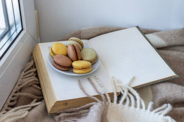 French dessert macaroons lie on a saucer on an open book, with a