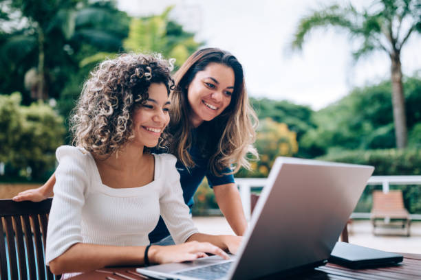 madre e figlia che usano il computer portatile nell'area della piscina - business relations foto e immagini stock