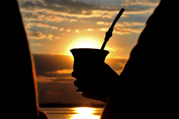 Silhouette of a yerba mate gourd drink Silhouette of hands holding a yerba mate traditional South American drink in a beautiful sunset view gaucho stock pictures, royalty-free photos & images