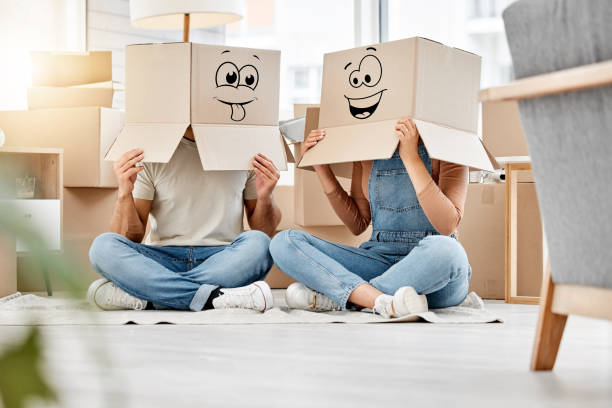 photo d’un couple portant des boîtes avec des visages souriants dessinés sur la tête lors d’un déménagement - cardboard box photos photos et images de collection