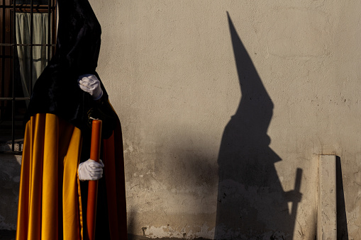 detail of the shadow of a nazarene on the wall during the holy week in sevilla, andalucia, spain. Catholic procession in a street of albaicin, granada.