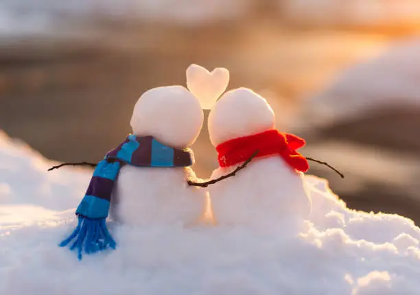 Photo of Cute snowman couple in love with snow heart between them.