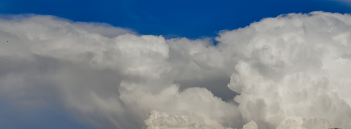 Panoramic image of a large white cumulus cloud floating under a blue sky - POA, SAO PAULO, BRAZIL.