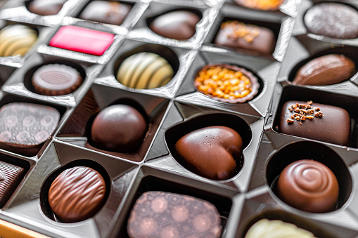 Macro closeup of box of chocolates truffles with luxury gourmet milk and dark desserts package with different heart shapes variety