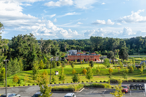 High angle view of summer landscape in Alachua, Florida near Gainesville with building cars parking lot and green trees with blue sky