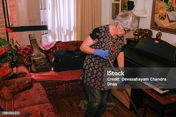 A Grey Haired Senior Latin American Lady Is Cleaning Her Living Room Before She Sets Up Her Christmas Tree Stock Photo - Download Image Now
