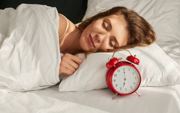 istock Young woman sleeping near alarm clock 1384054692