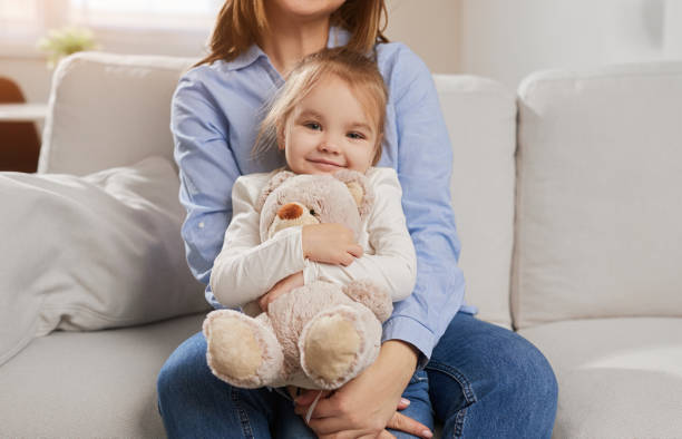 istock Crop mother hugging daughter on sofa 1384054742