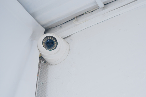 indoor security camera on a white wall under the ceiling