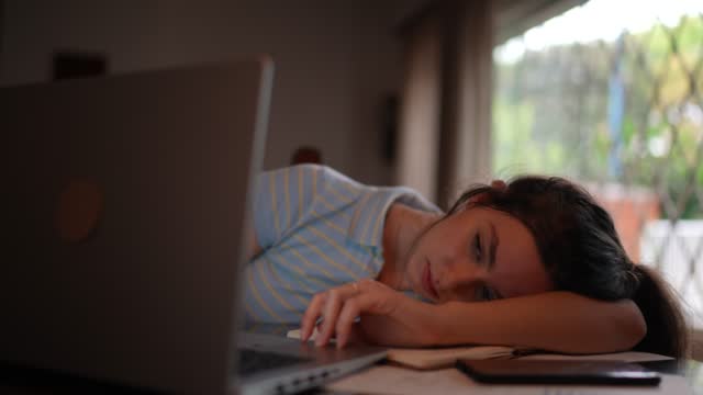 Tired young woman using laptop watching online class at home