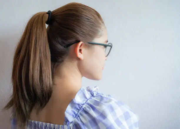 Photo of Young woman with ponytail hairstyle from side view.