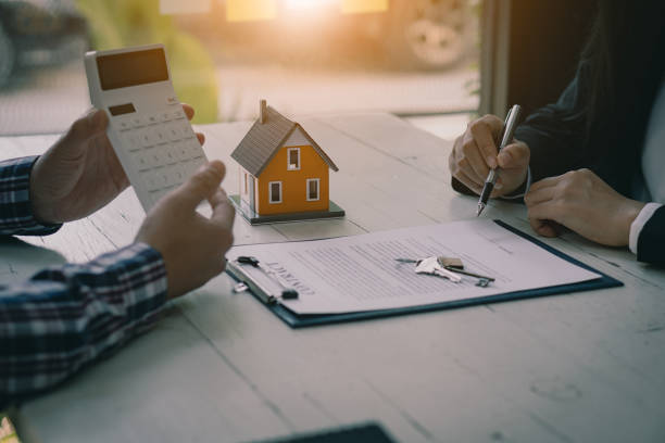 les professionnels de l’immobilier proposent à leurs clients des contrats pour discuter de l’achat d’une maison, d’une assurance ou d’un prêt immobilier. les agents de vente de maisons sont assis au bureau avec les acheteurs de maisons neuves a - contrat de bail photos et images de collection