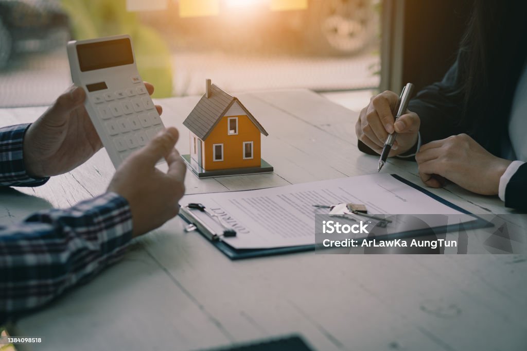 Real estate professionals offer their clients contracts to discuss home purchases, insurance or real estate loans. Home sales agents sit at the office with new home buyers in the office. Home Ownership Stock Photo