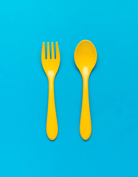 istock Bright yellow plastic spoon and fork on a blue background. Flat lay. 1384103788