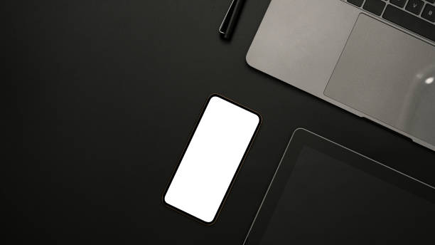 istock Modern black office desk with smartphone, laptop, tablet, and copy space. 1384108840