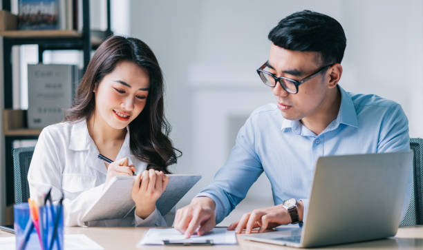 istock Two Asian businesspeople working at office 1384110502