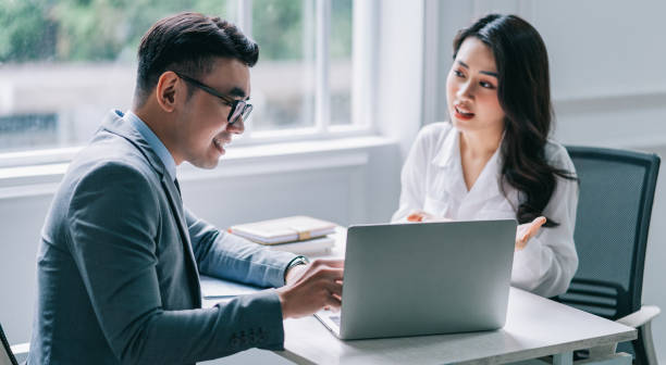 istock Two Asian businesspeople working at office 1384110605