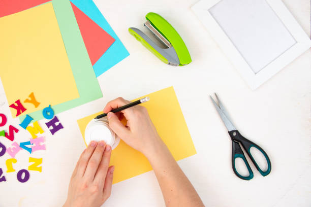 istock Female hands draw a circle with a pencil on yellow paper. Step by step instructions, top view. Step 2. 1384113865