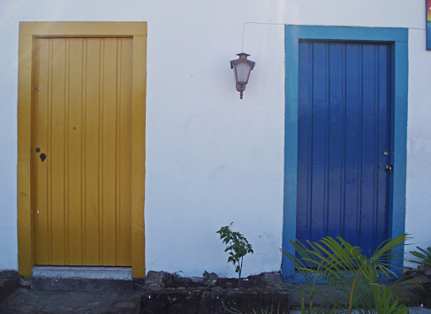Two doors in Paraty, Brazil.  One Yellow.  One Blue.   White building.