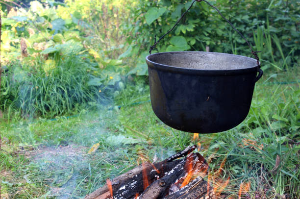 A bonfire with a hanging pot burns on the river