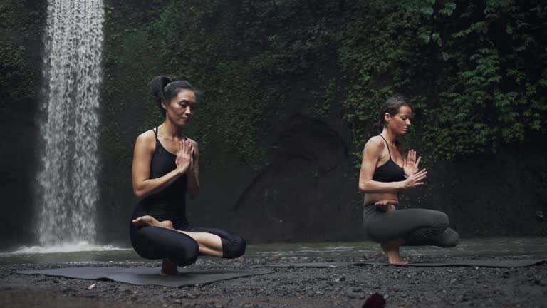 Two girl practice toe stand yoga asana background waterfall rapid slow motion