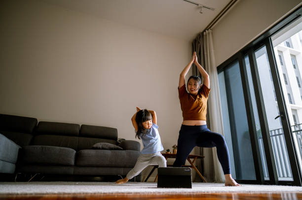 asian mother and little girl are doing sport exercises with laptop at home - exercício de relaxamento imagens e fotografias de stock