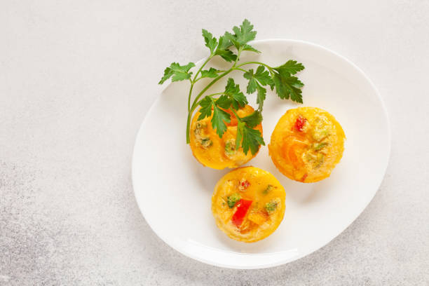 istock Egg muffins ( bites) and parsley leaves  in a plate on a gray background. Top view 1384131700