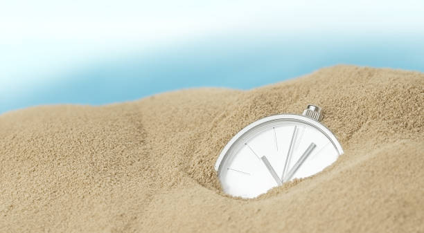 Pocket watch on a beach in the sand with blue sky and copy space