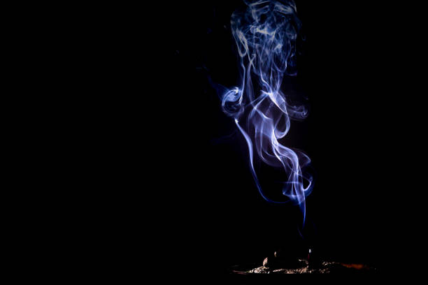 Closeup of smoke from burning incense stick on black background