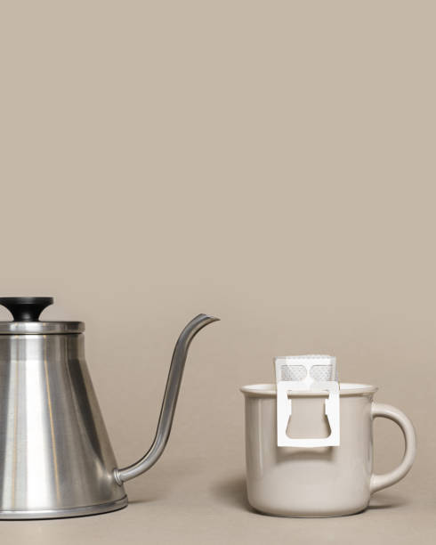 istock Drip coffee bag with ground coffee in big cup, hot water is poured into paper filter drip coffee for brewing on beige color background, quick way to brew ground coffee 1384136454
