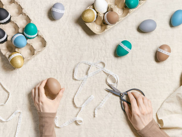istock Decoration colored Easter eggs, prepare for Happy Easter celebration, woman decorating dyed chicken egg with tape lace on table linen Lifestyle aesthetic photo at home, diy holiday 1384136468