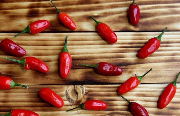 istock Red hot peppers are scattered on a wooden background. 1384143855