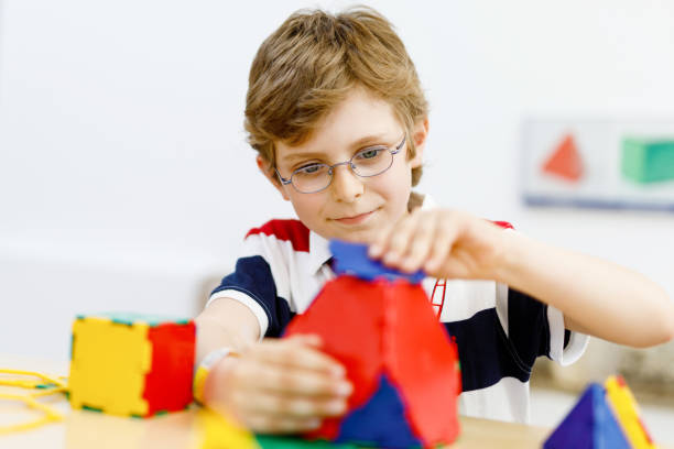 istock Happy kid boy with glasses having fun with building and creating geometric figures, learning mathematics and geometry 1384143863