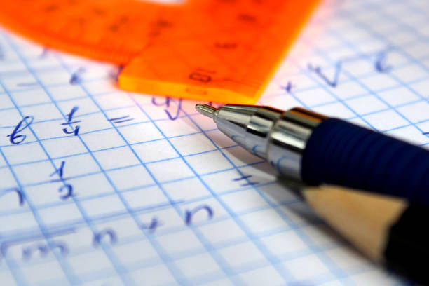A pencil and a pen lie on a notebook sheet with mathematical numbers.
