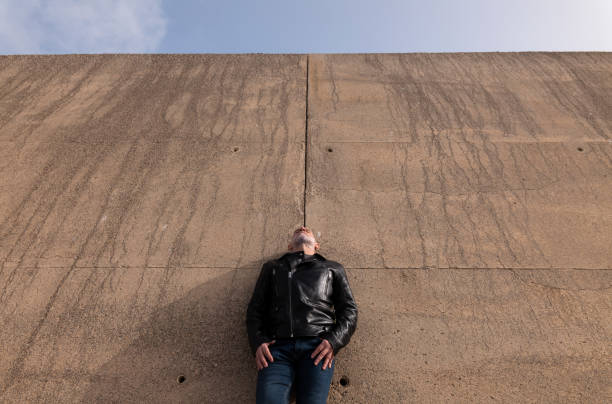 Adult man in leather jacket standing against wall