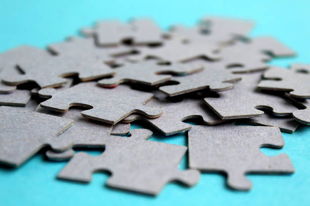 istock A pile of gray puzzle pieces lie on a blue background. 1384145176