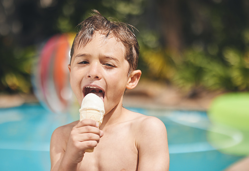 Portrait of cute Caucasian boy eating ice cream, with his brother in background