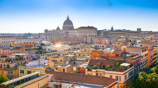 A suggestive cityscape on the roofs of the Prati district in the historic center of Rome near the Vatican City and St. Peter's Basilica (on the horizon). Prati is a historic and elegant quarter built at the end of the 19th century after the unification of Italy and the definition of Rome as the capital of the new nation, to host the growing population of the city and the state upper middle class. The Basilica of St. Peter's, in the Vatican, is the center of the Catholic religion, one of the most visited places in the world and in Rome for its immense artistic and architectural treasures. In 1980 the historic center of Rome was declared a World Heritage Site by Unesco. Super wide angle image in 16:9 and high definition format.