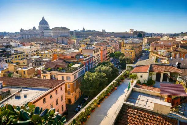 A suggestive cityscape on the roofs of the Prati district in the historic center of Rome near the Vatican City and St. Peter's Basilica (left on the horizon). Prati is a historic and elegant quarter built at the end of the 19th century after the unification of Italy and the definition of Rome as the capital of the new nation, to host the growing population of the city and the state upper middle class. The Basilica of St. Peter's, in the Vatican, is the center of the Catholic religion, one of the most visited places in the world and in Rome for its immense artistic and architectural treasures. In 1980 the historic center of Rome was declared a World Heritage Site by Unesco. Super wide angle image in high definition format.
