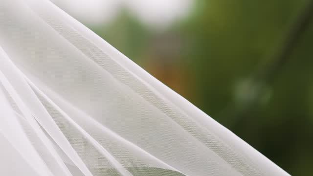 White chiffon fabric waving in wind on green background