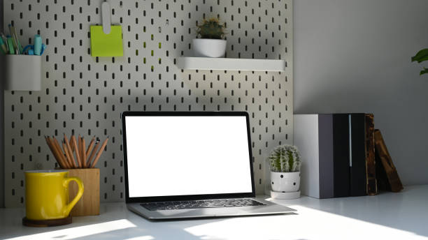 istock Laptop computer, pencil holder, coffee cup and potted plant on white table. Blank screen for your text message or information content. 1384152371