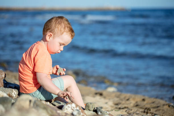 Cute little boy playing with pebble at the beach