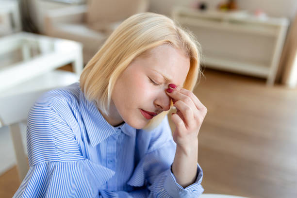 istock Feeling exhausted. Frustrated young woman looking exhausted while sitting at her working place and carrying her glasses in hand 1384158370